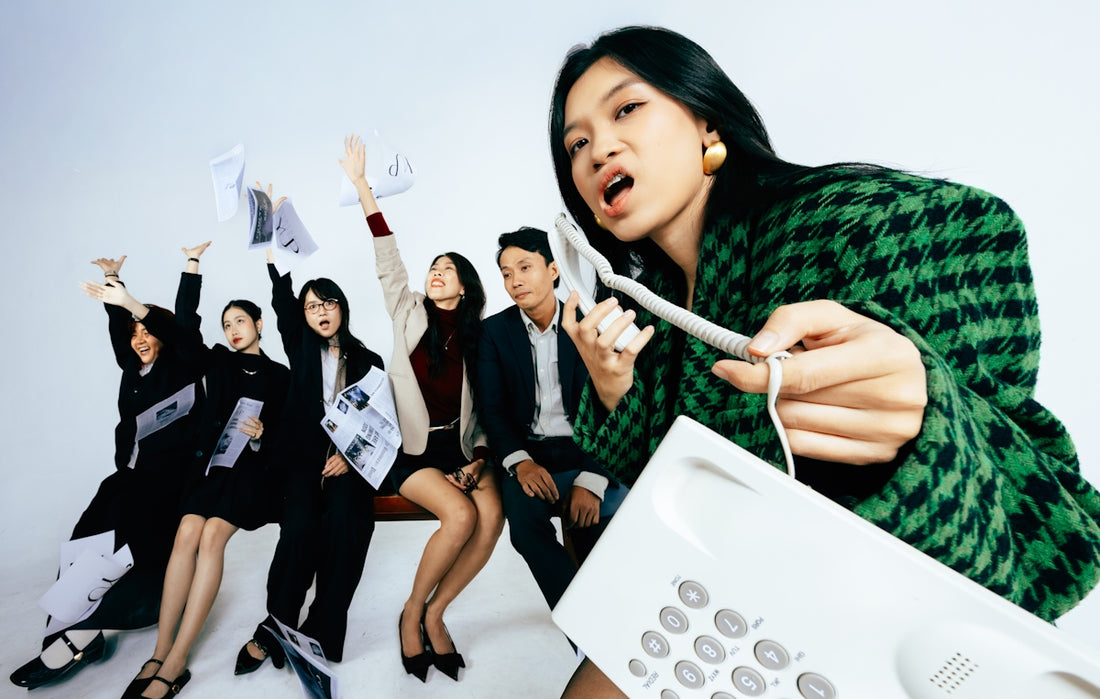 Frustrated woman holding telephone receiver with colleagues in background